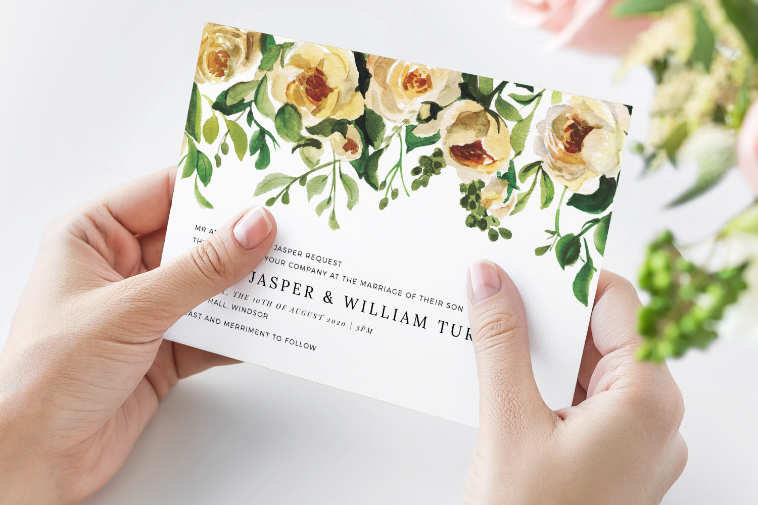 Wedding invitations with elegant yellow floral design held in hands, featuring green leaves and modern typography.