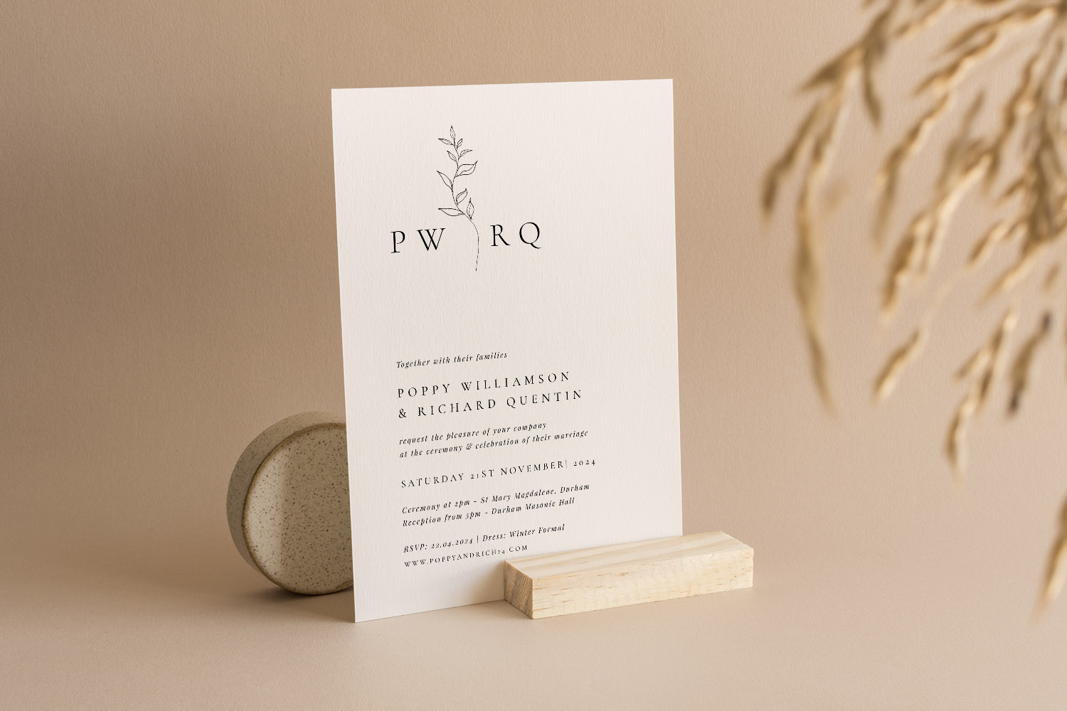 Wedding invitations with minimalist botanical design, black text on white card, displayed upright on a neutral background