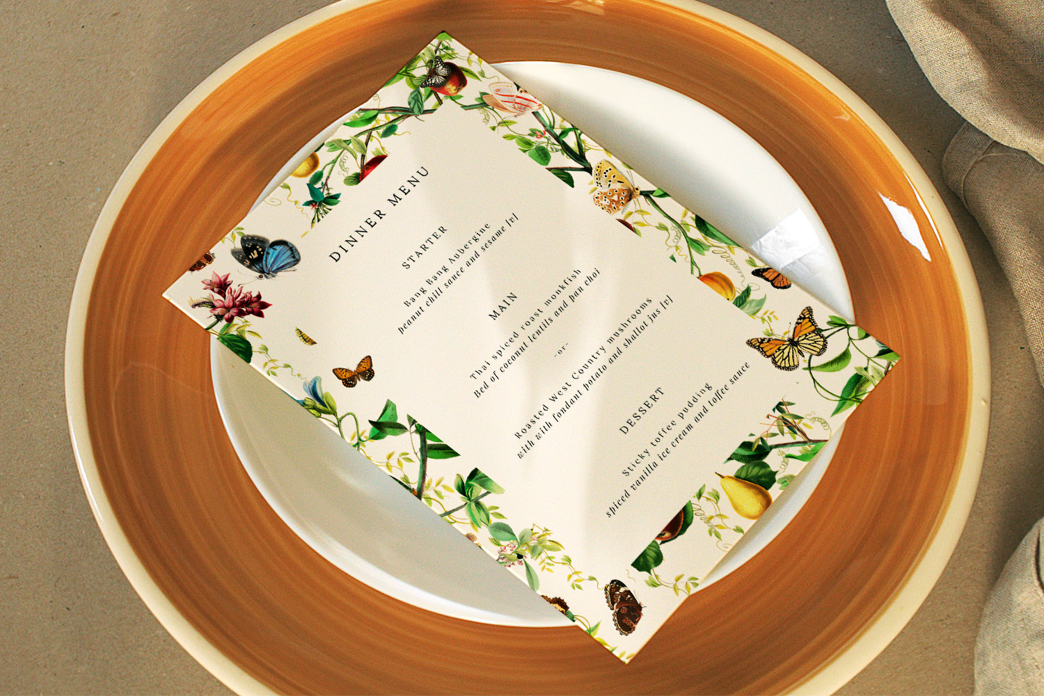 Wedding menus with botanical and butterfly border design displayed on a white plate with a brown rim, flat-lay view.