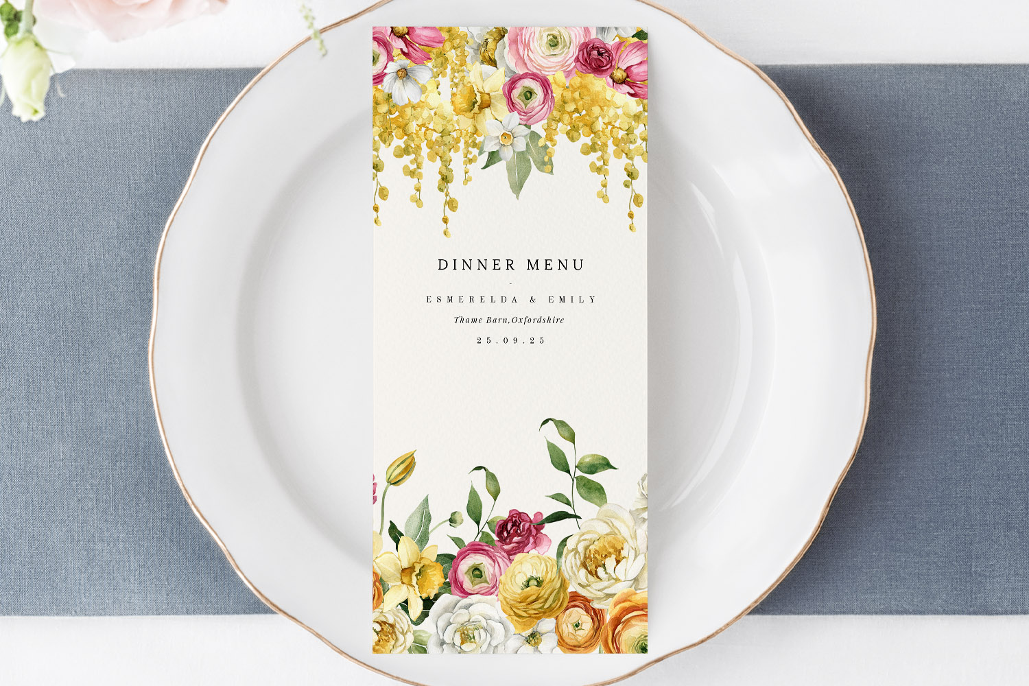 Wedding menus with elegant floral design placed on a white plate, featuring personalised names and event details.