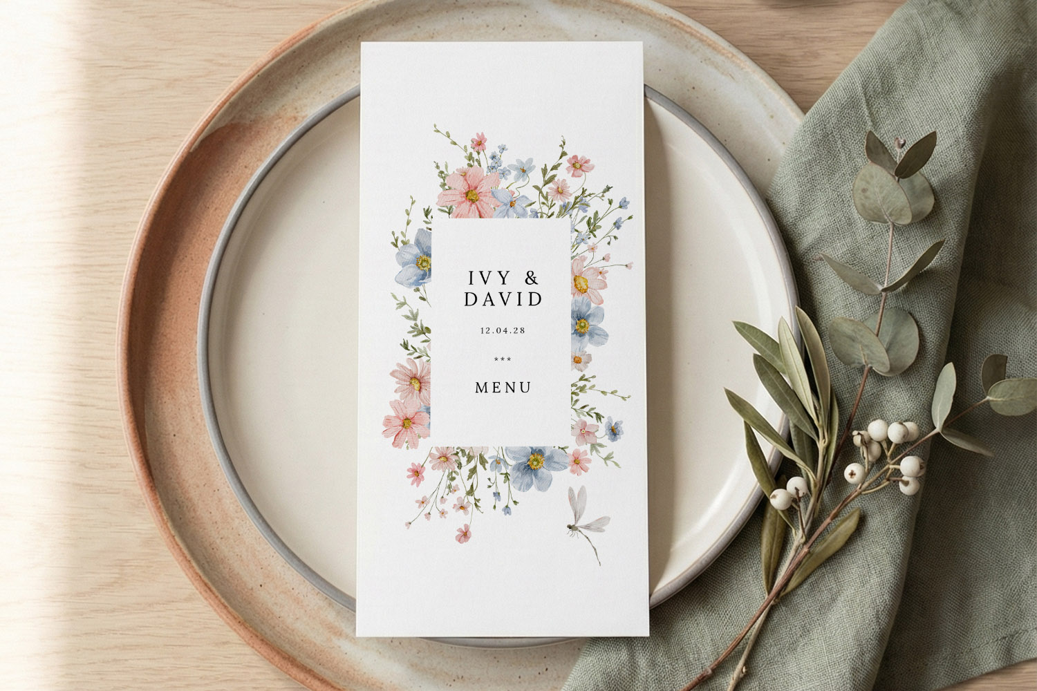 Wedding menus with pastel floral design, personalised names and date, displayed on a ceramic plate with green foliage