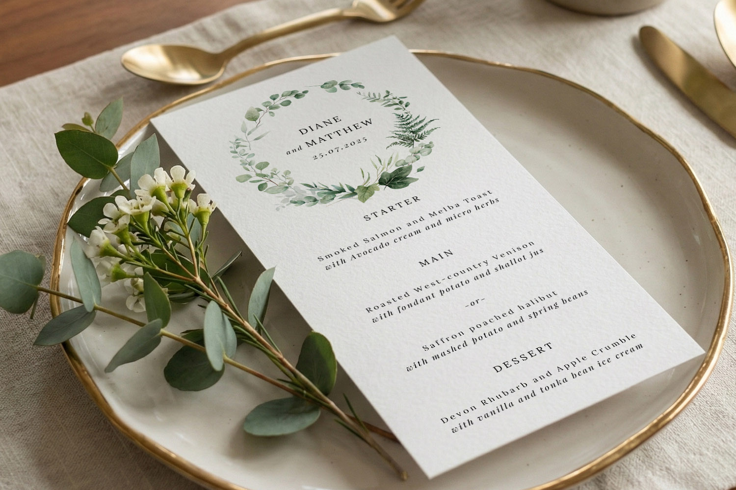 Wedding menus with elegant botanical design, printed on textured card and placed on a plate with gold cutlery and flowers.