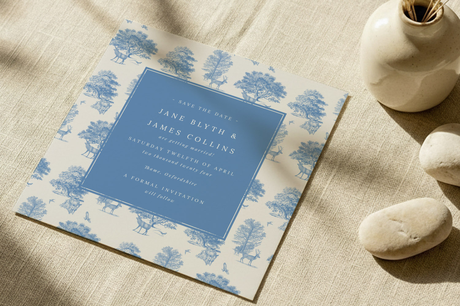 Wedding save the dates card with blue and white woodland design, featuring elegant typography on textured fabric background.