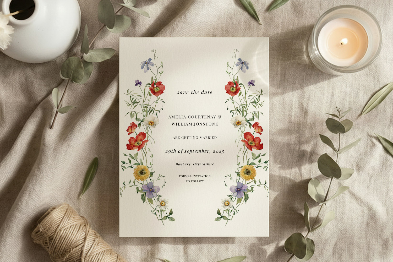 Wedding save the dates card with colourful wildflower border, elegant script text, and rustic flat-lay styling on linen