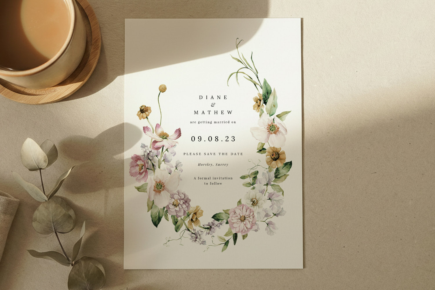 Wedding save the dates card with elegant floral wreath design, soft pastel flowers, and modern typography on a cream