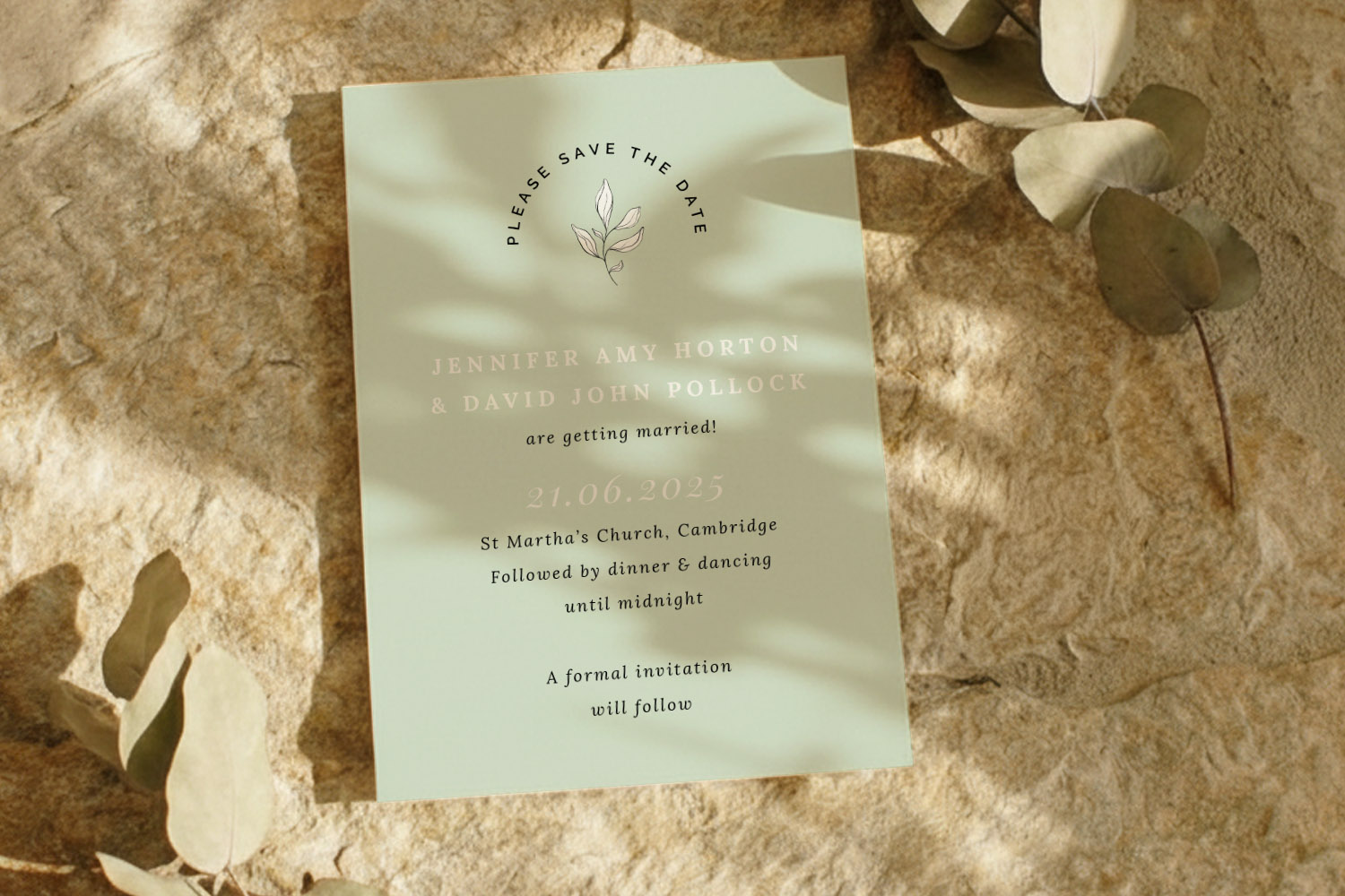 Wedding save the dates card with minimalist botanical design, soft green background and elegant gold text, styled on stone