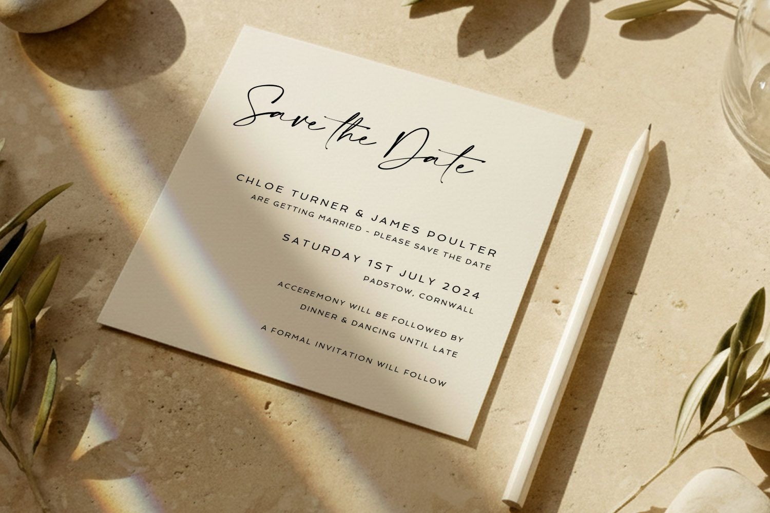 Wedding save the dates card with elegant black script and serif text on cream paper, styled on a stone surface with a white