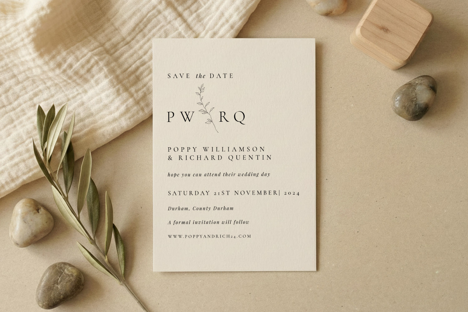Wedding save the dates card with minimalist botanical design on cream paper, styled with stones and olive branch on a
