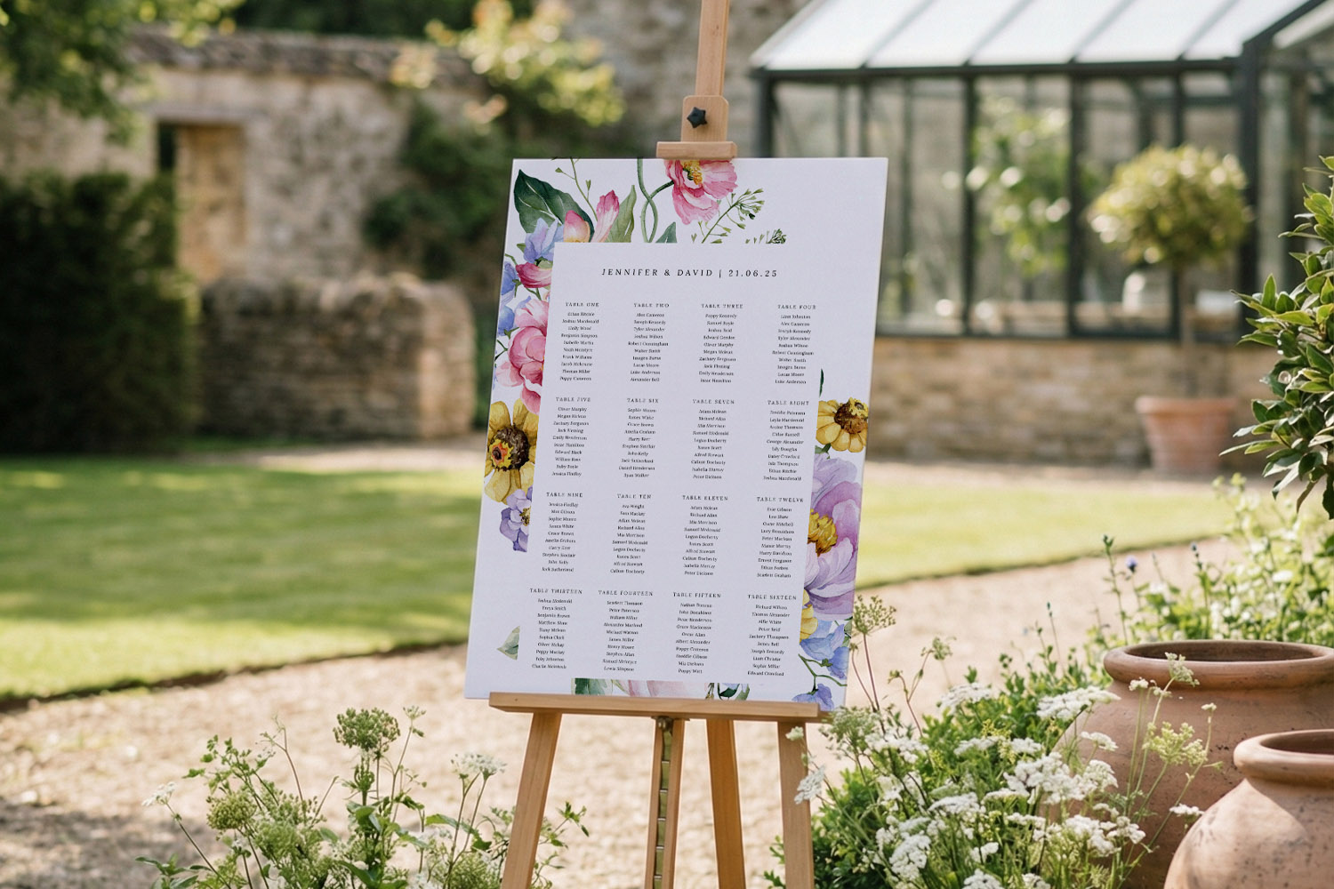 Wedding table plan with floral border displayed on a wooden easel outdoors in a garden venue setting