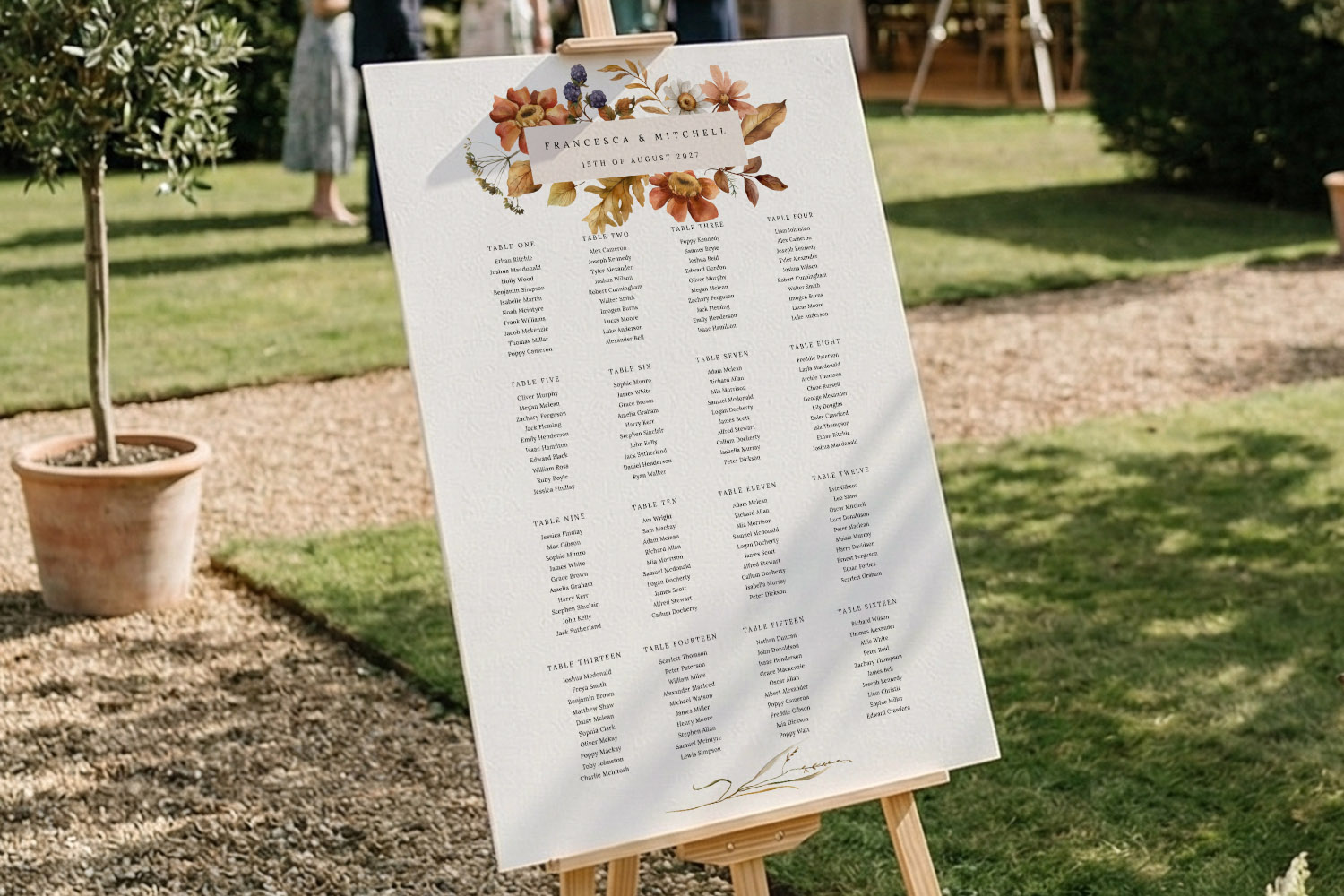 Wedding table plan with autumn floral design displayed on an easel outdoors, featuring guest names and table numbers.