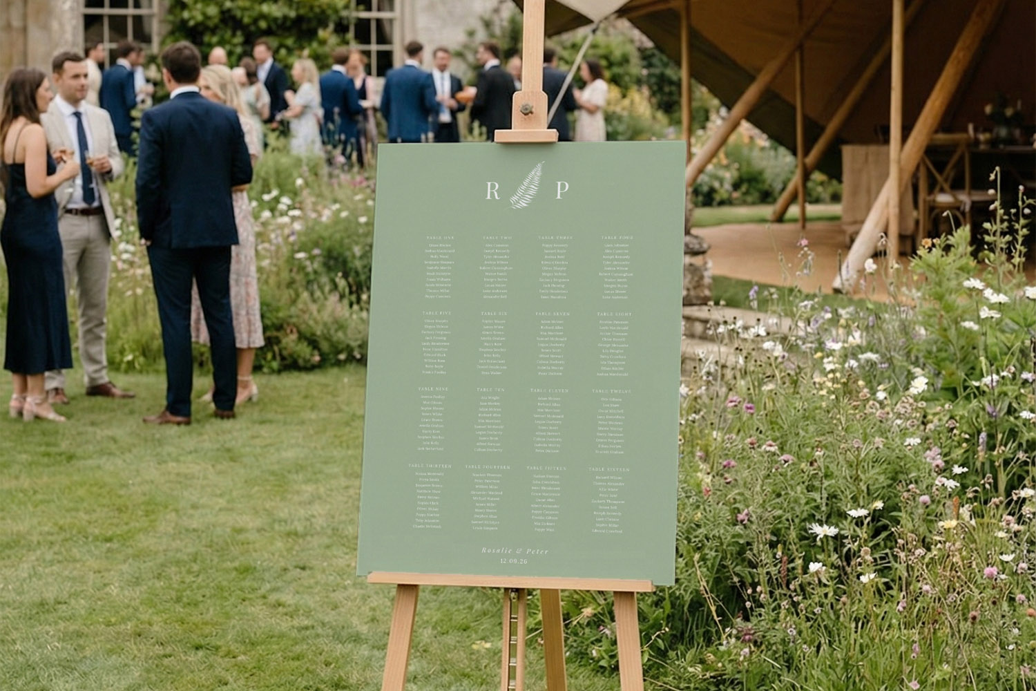 Wedding table plan with green background and white text displayed on an easel at an outdoor garden reception venue