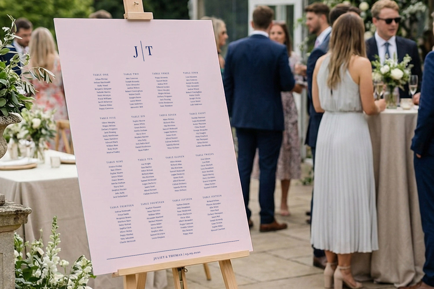 Wedding table plan with guest names printed on a large blush pink board displayed on an easel at an outdoor reception
