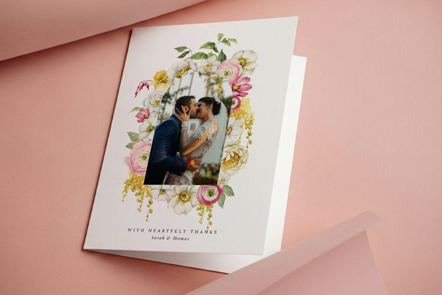 Wedding thank you cards featuring a floral border and a couple's photo, displayed on a soft pink background with an open