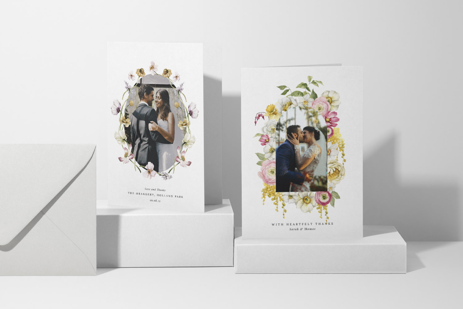 Wedding thank you cards featuring floral borders and personalised couple photos, displayed with matching white envelopes on