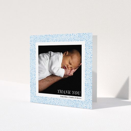 A baby card named 'Blue Floral Frame'. It is a square (148mm x 148mm) card in a square orientation. It is a photographic baby card with room for 1 photo. 'Blue Floral Frame' is available as a folded card, with tones of blue and white.