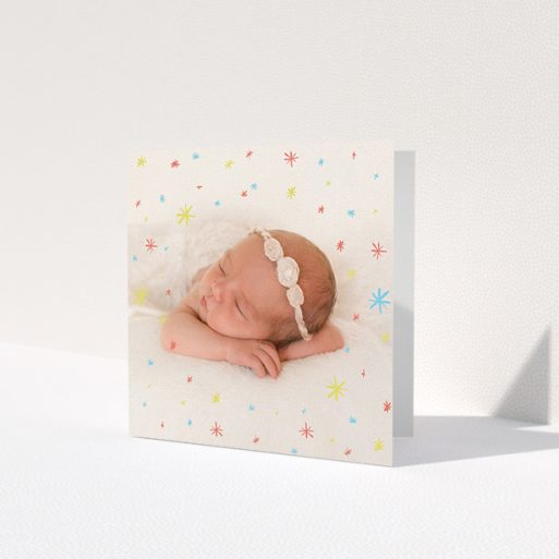 A baby card design named 'Playground Sparkles'. It is a square (148mm x 148mm) card in a square orientation. It is a photographic baby card with room for 1 photo. 'Playground Sparkles' is available as a folded card, with mainly red colouring.