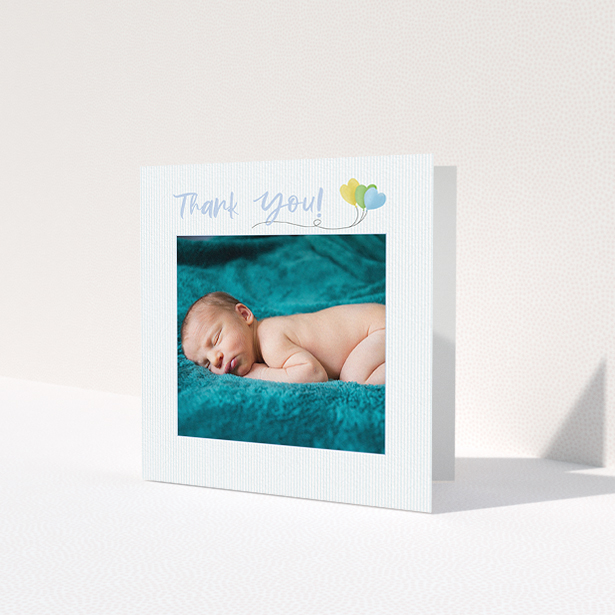 A baby thank you card design named "Balloooons". It is a square (148mm x 148mm) card in a square orientation. It is a photographic baby thank you card with room for 1 photo. "Balloooons" is available as a folded card, with mainly blue colouring.