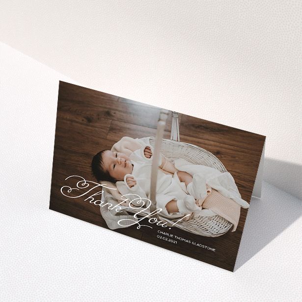 A baby thank you card called "Flourished Thank You". It is an A5 card in a landscape orientation. It is a photographic baby thank you card with room for 1 photo. "Flourished Thank You" is available as a folded card, with mainly white colouring.