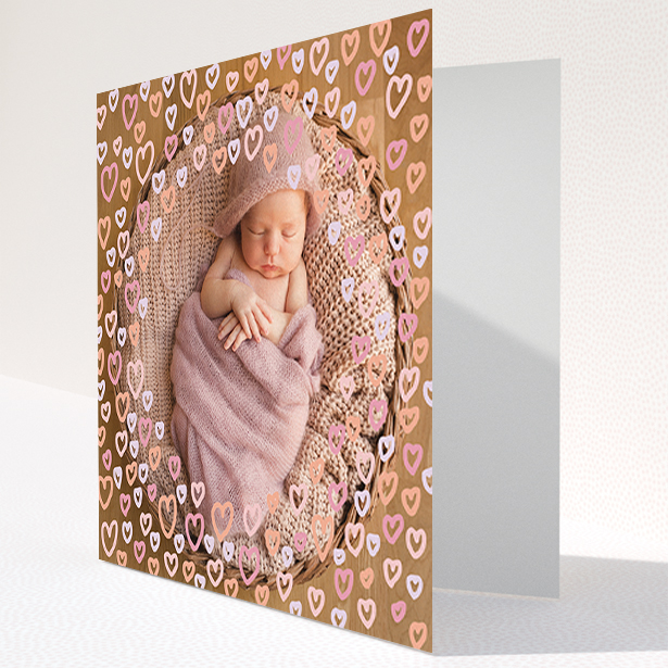 A baby thank you card design titled "Heart Overlay". It is a square (148mm x 148mm) card in a square orientation. It is a photographic baby thank you card with room for 1 photo. "Heart Overlay" is available as a folded card, with mainly pink colouring.