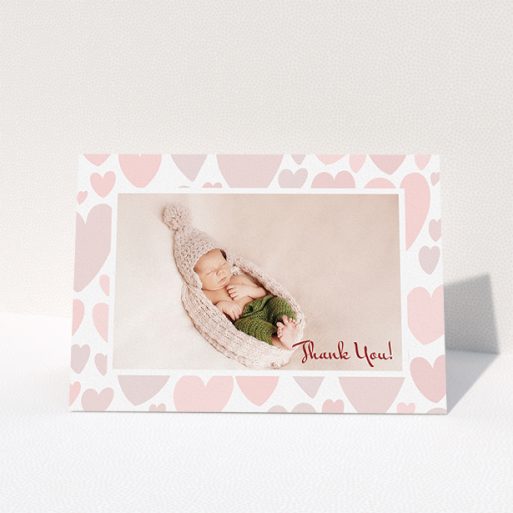 A baby thank you card named "Pastel Hearts". It is an A5 card in a landscape orientation. It is a photographic baby thank you card with room for 1 photo. "Pastel Hearts" is available as a folded card, with tones of pink and white.