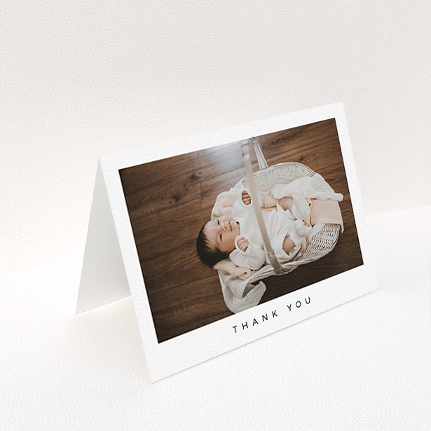 A baby thank you card design named "Simple". It is an A6 card in a landscape orientation. It is a photographic baby thank you card with room for 1 photo. "Simple" is available as a folded card, with mainly white colouring.