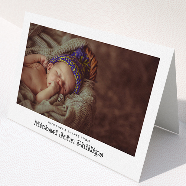 A baby thank you card named "Simple Photo Frame". It is an A5 card in a landscape orientation. It is a photographic baby thank you card with room for 1 photo. "Simple Photo Frame" is available as a folded card, with mainly white colouring.