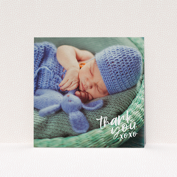 A baby thank you card design named "Thanks In the Corner". It is a square (148mm x 148mm) card in a square orientation. It is a photographic baby thank you card with room for 1 photo. "Thanks In the Corner" is available as a flat card, with mainly white colouring.