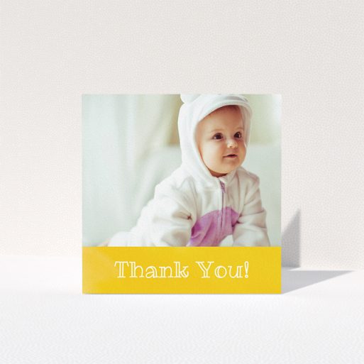 A baby thank you card template titled "Thanks In Yellow". It is a square (148mm x 148mm) card in a square orientation. It is a photographic baby thank you card with room for 1 photo. "Thanks In Yellow" is available as a folded card, with tones of yellow and white.