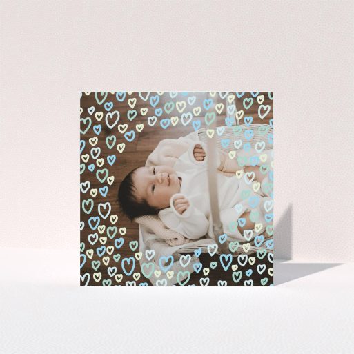 Baptism Thank You Card Design - "Blue Hearts" A baptism thank you card template titled "Blue Hearts". It is a square (148mm x 148mm) card in a square orientation. It is a photographic baptism thank you card with room for 1 photo. "Blue Hearts" is available as a folded card, with tones of blue, light blue and green.