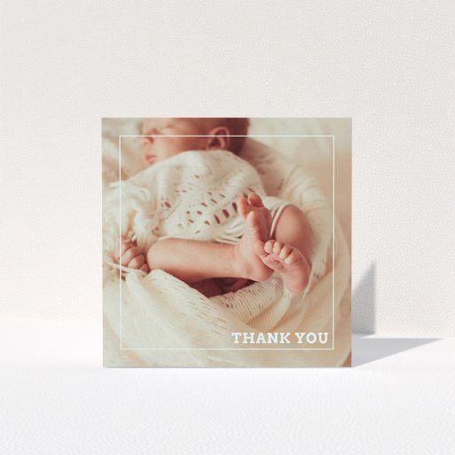 A baptism thank you card named "Over Photo Frame". It is a square (148mm x 148mm) card in a square orientation. It is a photographic baptism thank you card with room for 1 photo. "Over Photo Frame" is available as a folded card, with mainly pale pink colouring.