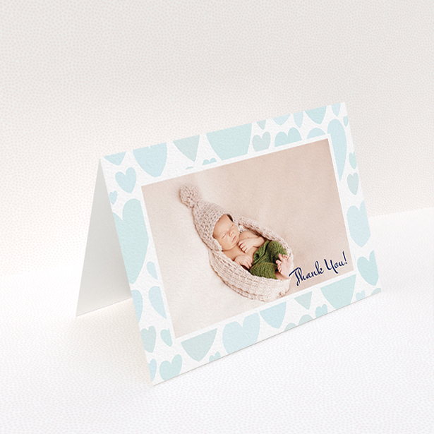 A baptism thank you card named "Pastel Hearts". It is an A6 card in a landscape orientation. It is a photographic baptism thank you card with room for 1 photo. "Pastel Hearts" is available as a folded card, with tones of blue and white.