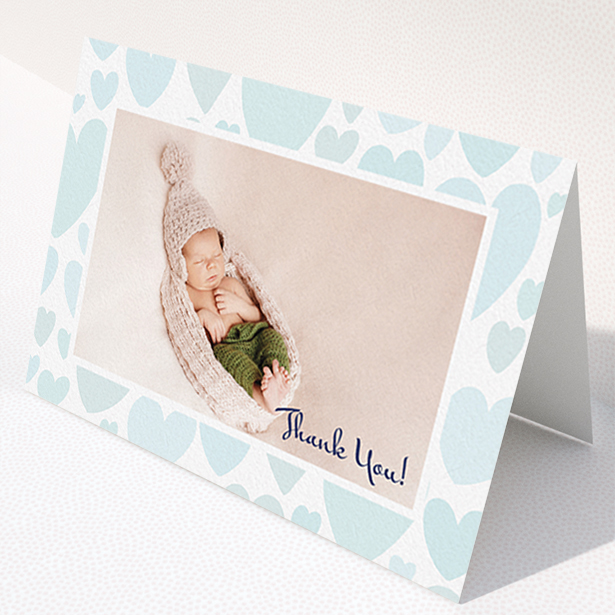A baptism thank you card named "Pastel Hearts". It is an A6 card in a landscape orientation. It is a photographic baptism thank you card with room for 1 photo. "Pastel Hearts" is available as a folded card, with tones of blue and white.