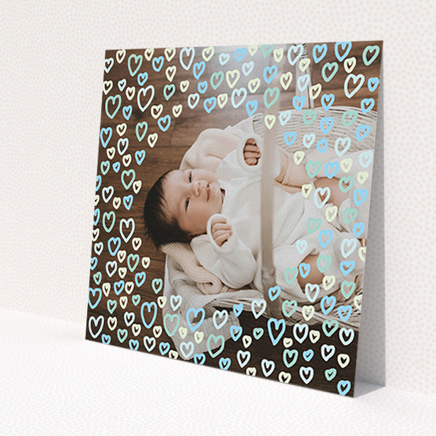 A birth announcement card design called "Blue Hearts". It is a square (148mm x 148mm) card in a square orientation. It is a photographic birth announcement card with room for 1 photo. "Blue Hearts" is available as a flat card, with mainly blue colouring.
