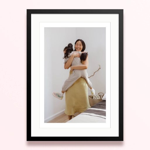 Framed and mounted photo print with one photo of a woman hugging a child in a bright room.