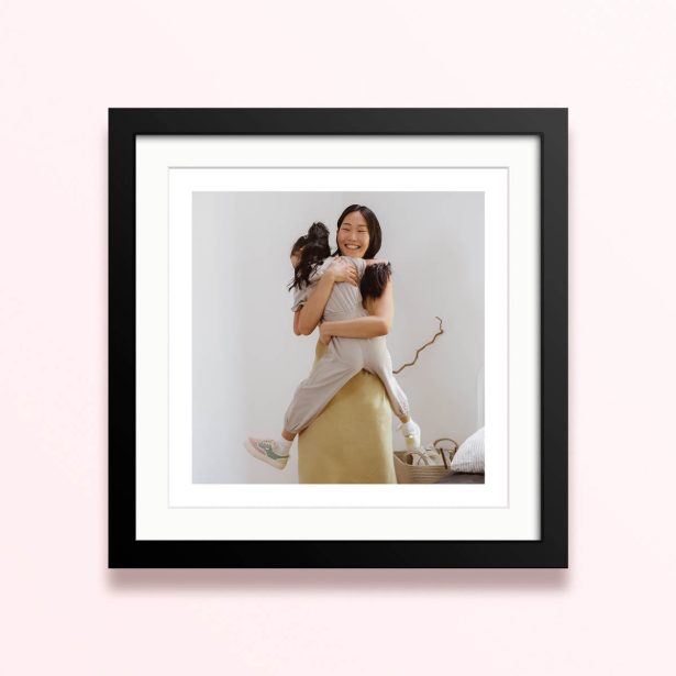 Framed and mounted photo print with one photo of a woman hugging a child in a bright room.