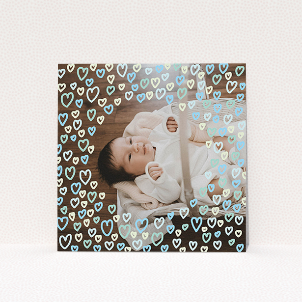 A christening invitation design titled "Blue Hearts". It is a square (148mm x 148mm) invite in a square orientation. It is a photographic christening invitation with room for 1 photo. "Blue Hearts" is available as a flat invite, with mainly blue colouring.