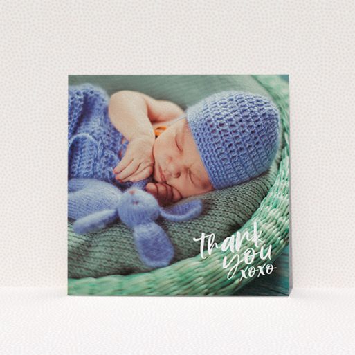 A christening thank you card template titled "Thanks In the Corner". It is a square (148mm x 148mm) card in a square orientation. It is a photographic christening thank you card with room for 1 photo. "Thanks In the Corner" is available as a flat card, with mainly white colouring.
