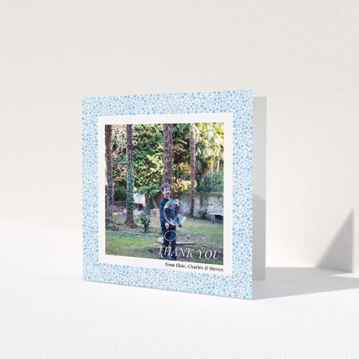 A communion thank you card design titled 'Blue Floral Frame'. It is a square (148mm x 148mm) card in a square orientation. It is a photographic communion thank you card with room for 1 photo. 'Blue Floral Frame' is available as a folded card, with tones of blue and white.
