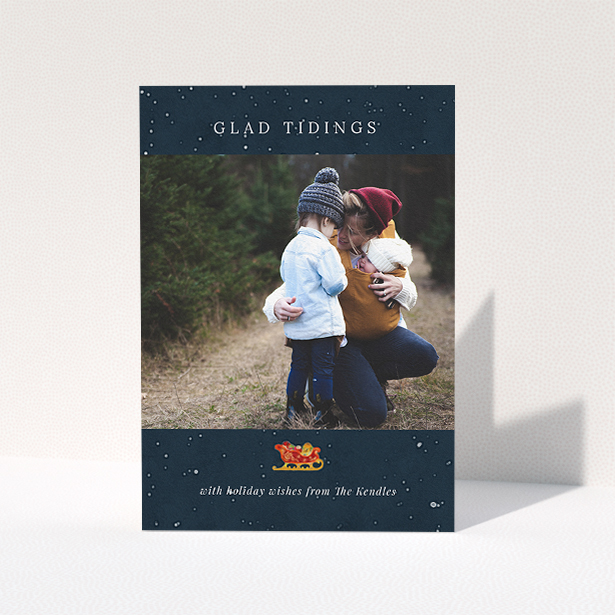 A custom christmas card design called "Glad Tidings with Sleigh". It is an A5 card in a portrait orientation. It is a photographic custom christmas card with room for 1 photo. "Glad Tidings with Sleigh" is available as a folded card, with tones of blue and white.