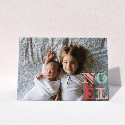A custom christmas card design named "Pastel Noel". It is an A5 card in a landscape orientation. It is a photographic custom christmas card with room for 1 photo. "Pastel Noel" is available as a folded card, with mainly pink colouring.
