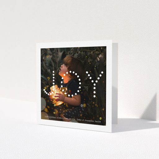 A family christmas card design titled 'Joy'. It is a square (148mm x 148mm) card in a square orientation. It is a photographic family christmas card with room for 1 photo. 'Joy' is available as a folded card, with mainly white colouring.