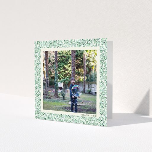A first holy communion thank you card named 'Hedgerow Frame'. It is a square (148mm x 148mm) card in a square orientation. It is a photographic first holy communion thank you card with room for 1 photo. 'Hedgerow Frame' is available as a folded card, with tones of green and white.