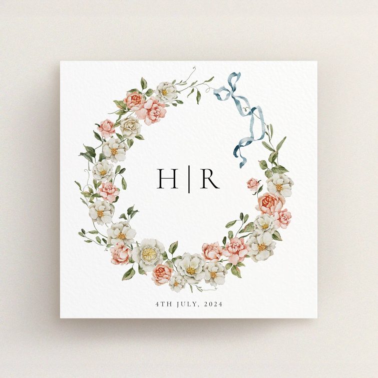 Floral wreath wedding invitation design with monogram and blue ribbon, no photos included.