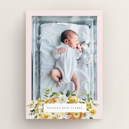 Floral design birth announcement card with a baby photo in a crib and colourful flowers.