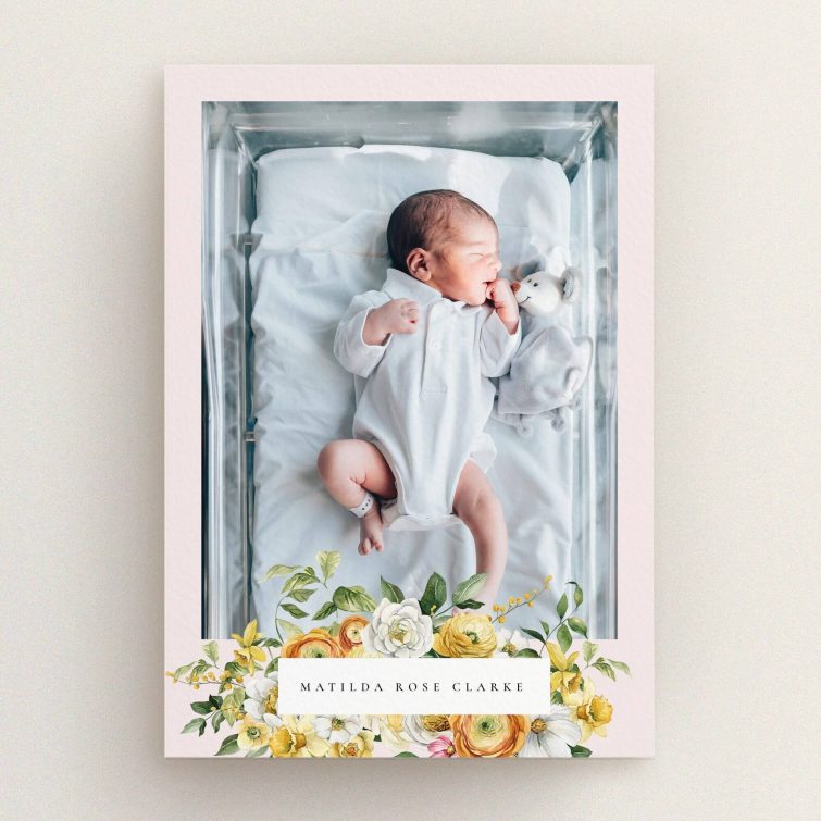 Floral design birth announcement card with a baby photo in a crib and colourful flowers.
