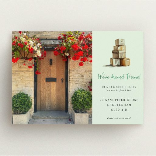 UK House Move Announcement Change of address card with a front door and floral decorations on the left and stacked moving boxes illustration on the right.