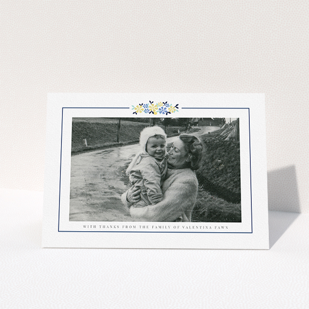 A funeral thank you card template titled "Remembered in flowers". It is an A5 card in a landscape orientation. It is a photographic funeral thank you card with room for 1 photo. "Remembered in flowers" is available as a folded card, with tones of white and blue.