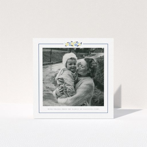 A funeral thank you card design titled "Remembered in flowers". It is a square (148mm x 148mm) card in a square orientation. It is a photographic funeral thank you card with room for 1 photo. "Remembered in flowers" is available as a folded card, with tones of white and blue.