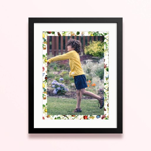 Framed and mounted photo print with coloured floral border featuring one photo of a child playing in a garden.