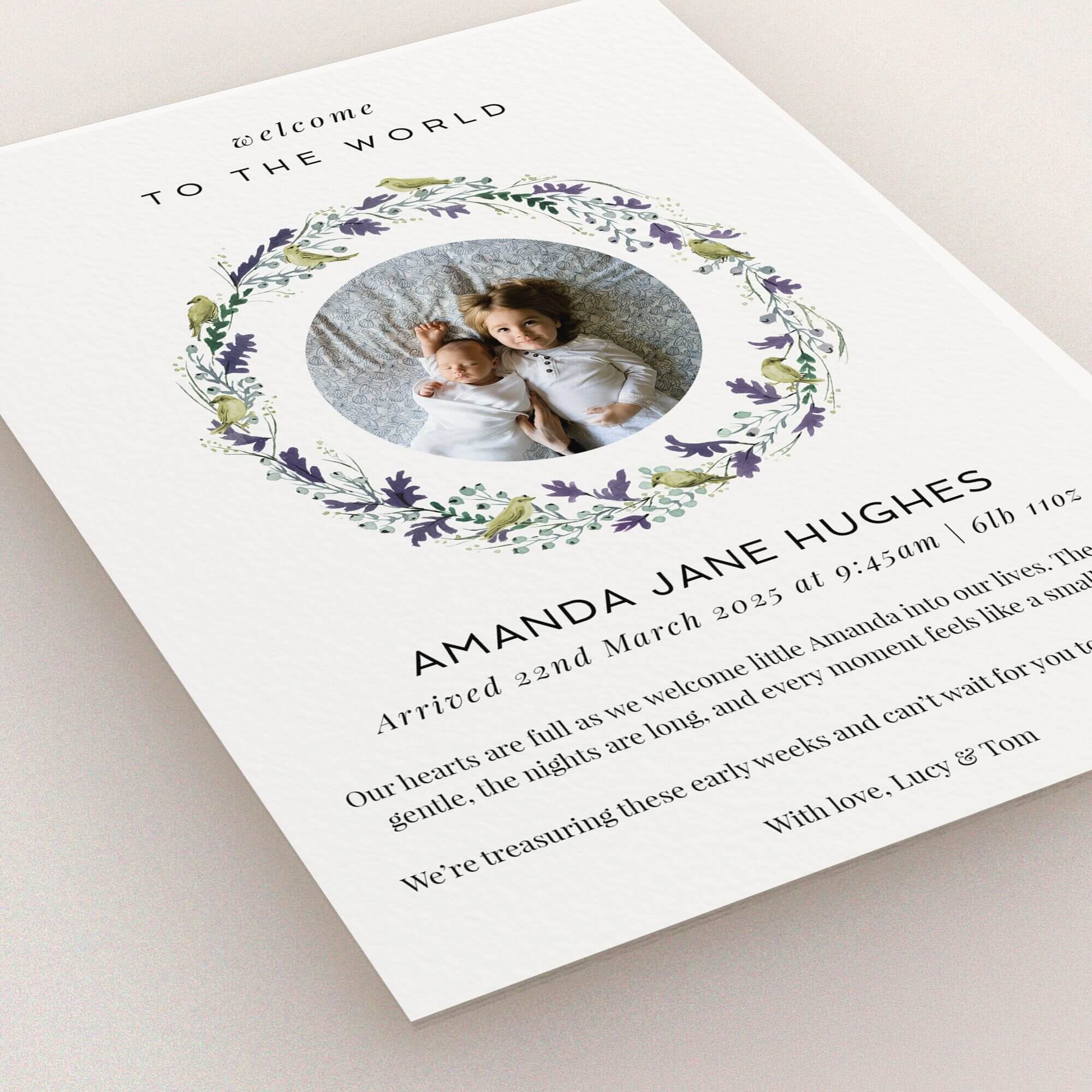 Floral wreath birth announcement card with two photos of siblings.